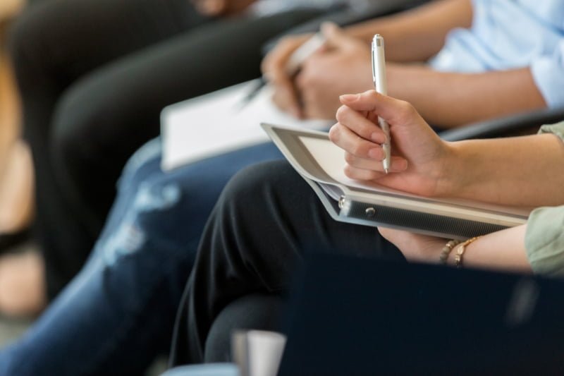 Man writing on a pad in a meeting